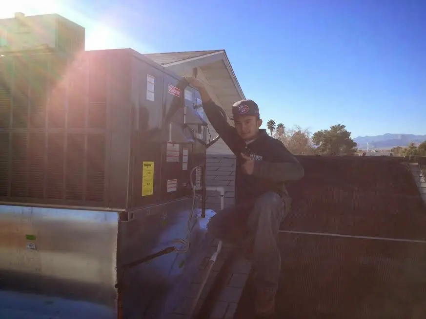 HVAC technician performing Air Duct Cleaning on a rooftop unit in Winterville
